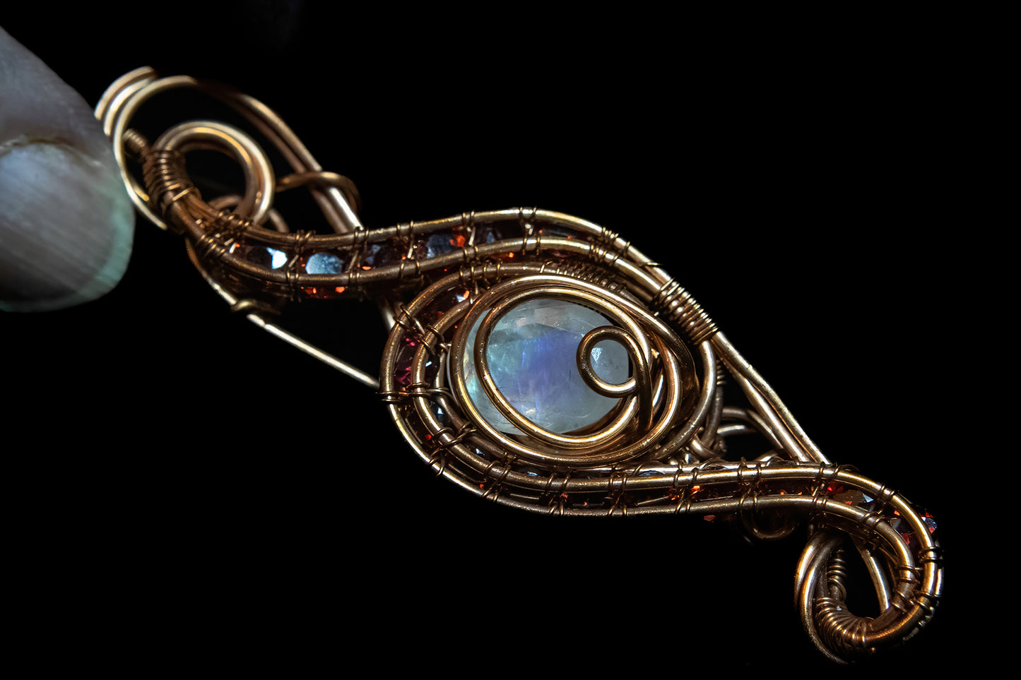 Faceted Madagascar Rainbow Flash Moonstone nestled in Fine Copper and surrounded by a multitude of Garnet Facets