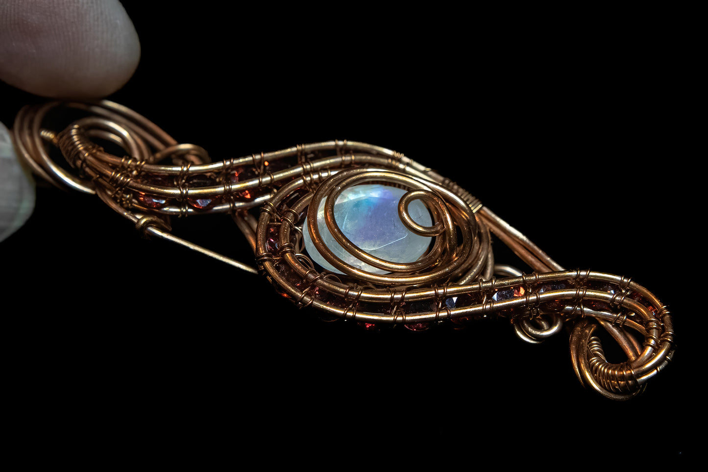 Faceted Madagascar Rainbow Flash Moonstone nestled in Fine Copper and surrounded by a multitude of Garnet Facets