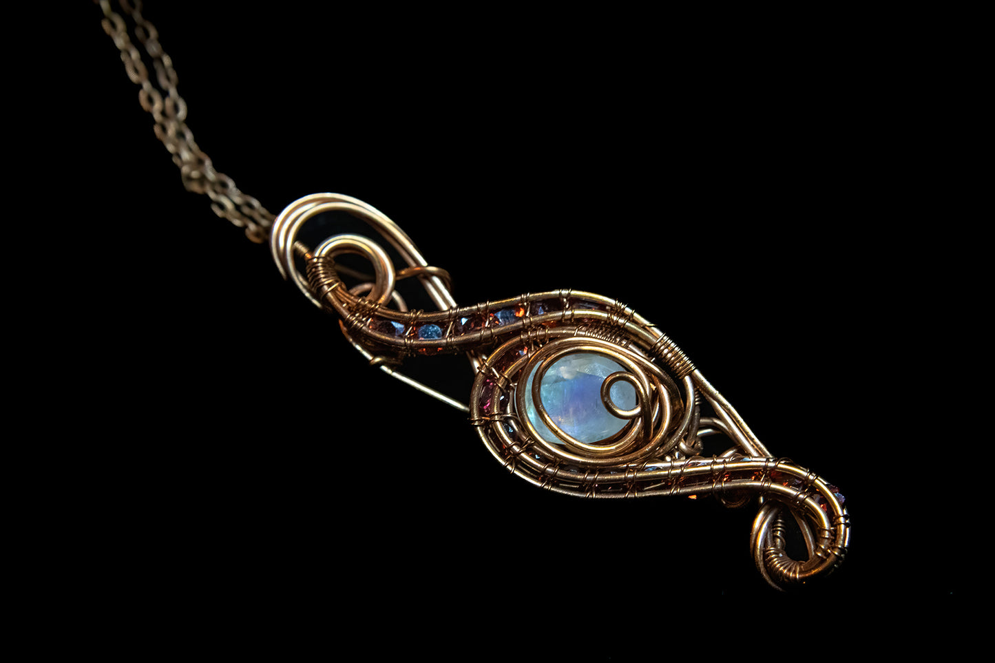 Faceted Madagascar Rainbow Flash Moonstone nestled in Fine Copper and surrounded by a multitude of Garnet Facets