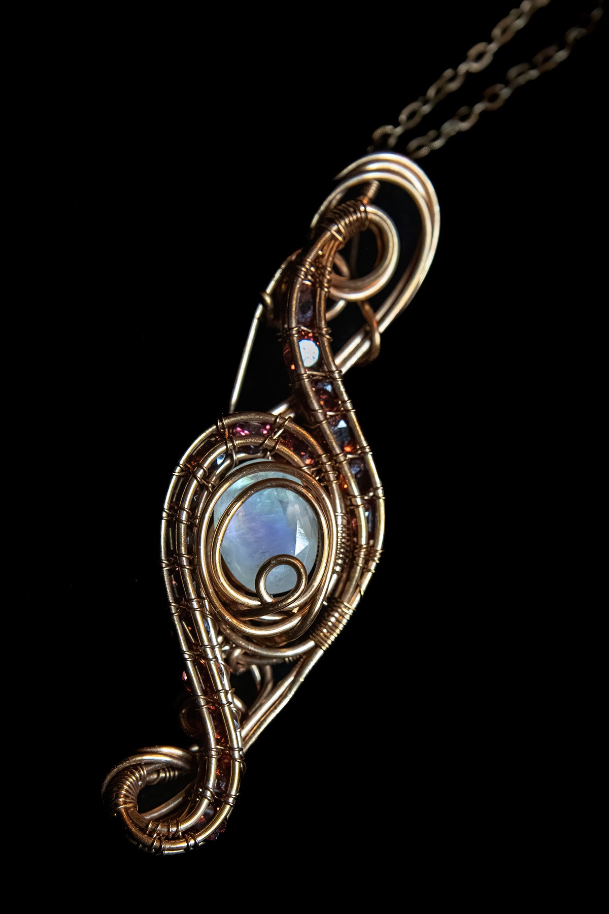 Faceted Madagascar Rainbow Flash Moonstone nestled in Fine Copper and surrounded by a multitude of Garnet Facets